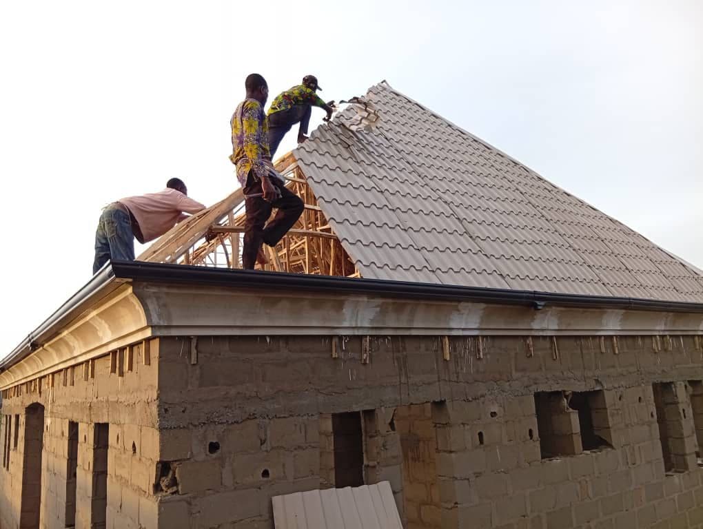 Workers installing 0.55mm long span aluminium roofing sheets on site in Lagos