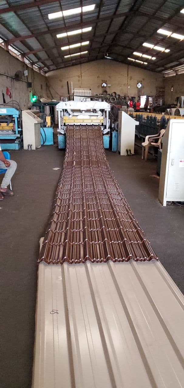 Corrugation machine producing aluminium roofing sheet profiles at Gods Promise Aluminium factory.